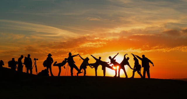 Een foto van mensen in silhouetten tegen de zonsondergang. 