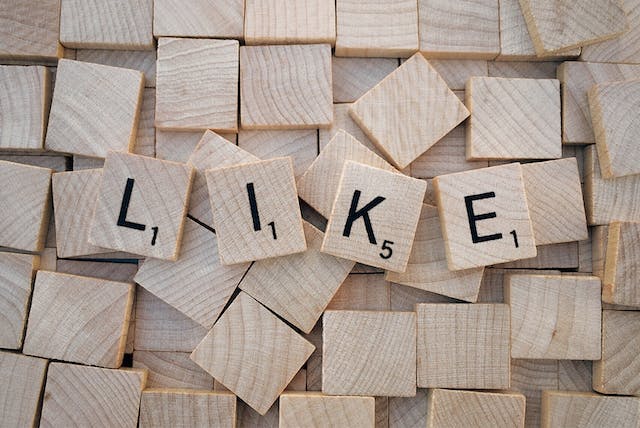 Houten lettertegels spellen het woord "LIKE".