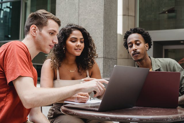 Drei junge Erwachsene durchsuchen Online-Inhalte auf ihren Laptops. 