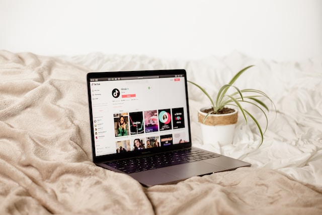 An image of a laptop on a bed showing TikTok’s official account with over 60 million followers.
