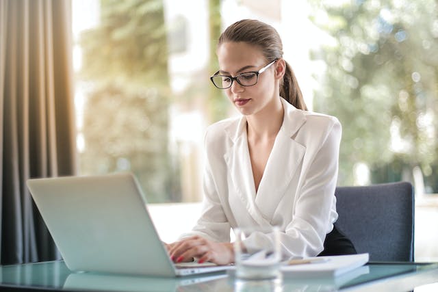 An image of a young professional typing on her laptop in her office. 
