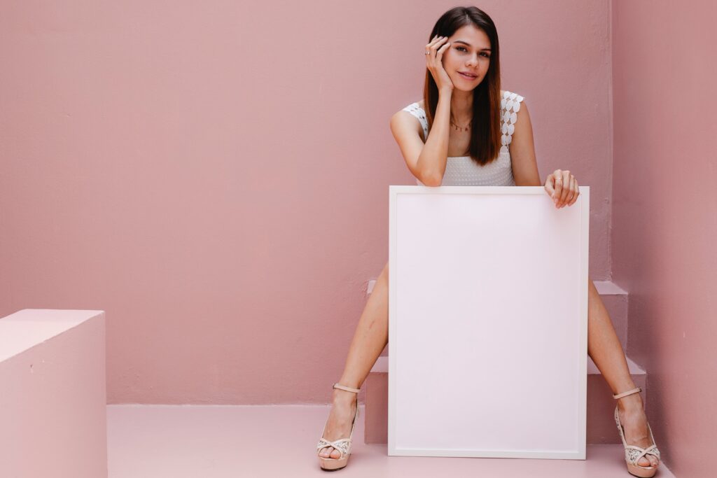 Une femme est assise sur un escalier et tient une toile vierge pour une publicité. 