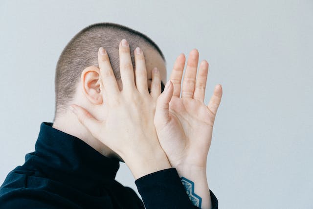 Uma pessoa cobre o rosto com as mãos. 