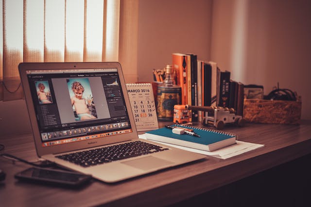 An image of a desk with a laptop featuring a video still in the midst of editing.