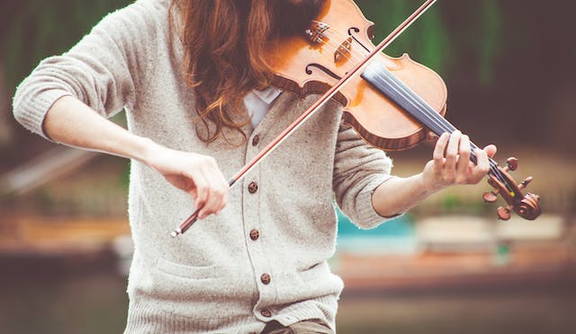 A close-up image of a woman playing the violin. 
