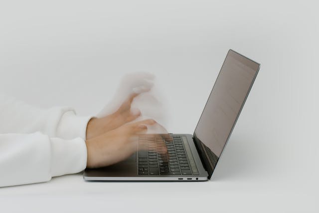 A timelapse image showing hands typing on a laptop keyboard. 