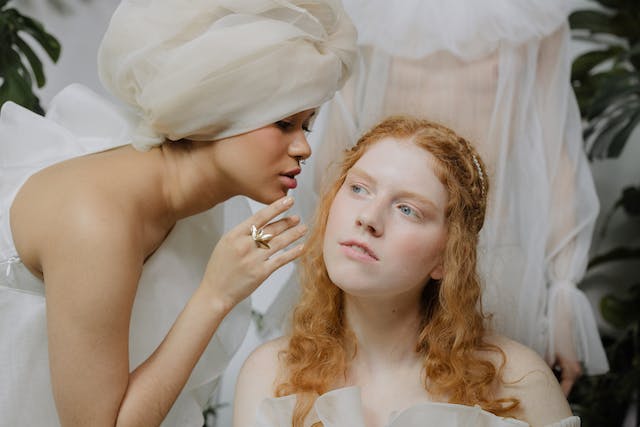 A close-up shot of a woman whispering to another woman. 