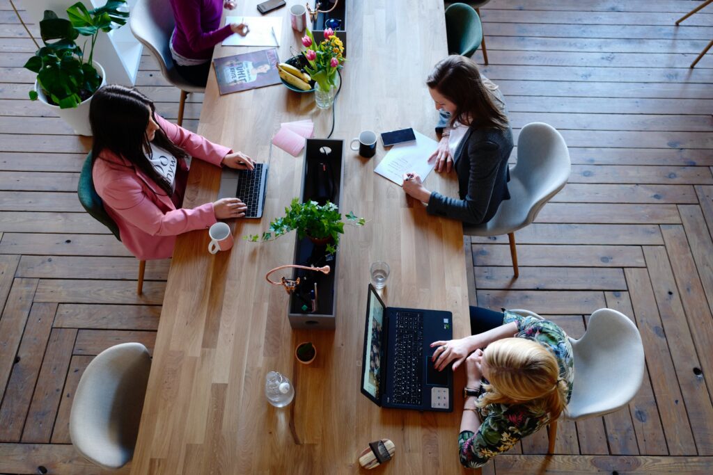 Een overheadbeeld van een groep vrouwen aan het werk in een kantoor. 