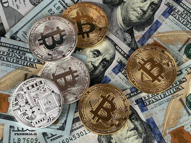 Una imagen de monedas de plata y oro sobre billetes de un dólar. 