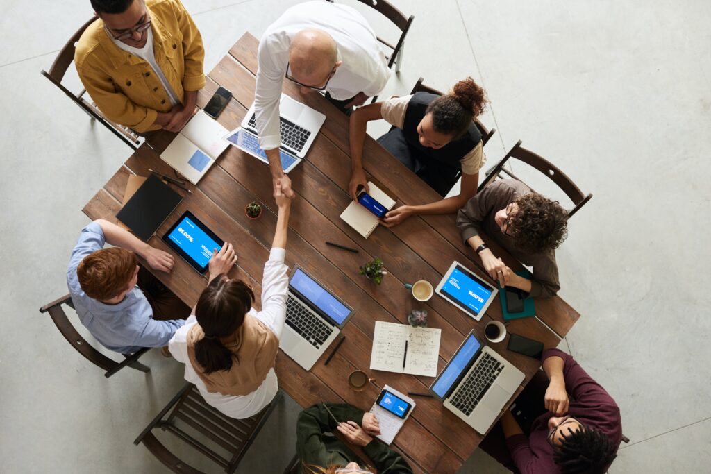 Un'inquadratura dall'alto di un gruppo di persone sedute intorno a un tavolo per una riunione di lavoro. 