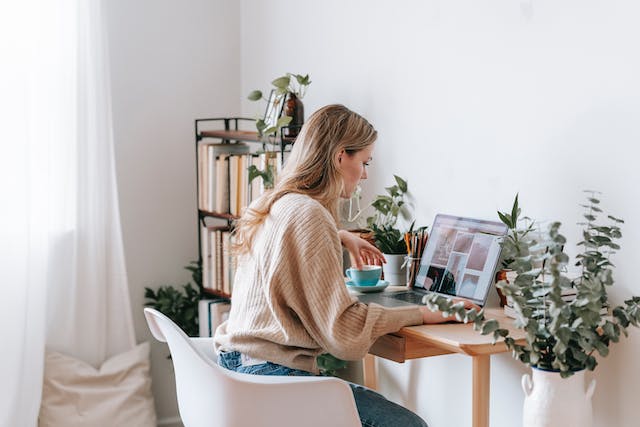 Een vrouw bladert door foto's op haar laptop om een TikTok-diavoorstelling te maken. 