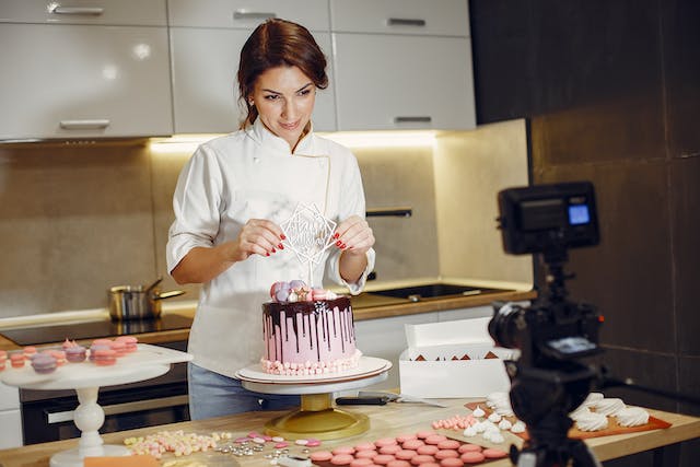 Een vrouw filmt zichzelf terwijl ze een taart versiert. 
