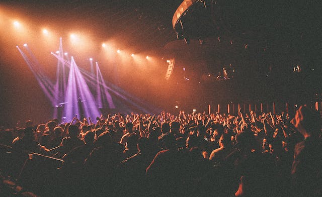 A massive crowd cheers while watching a live concert. 