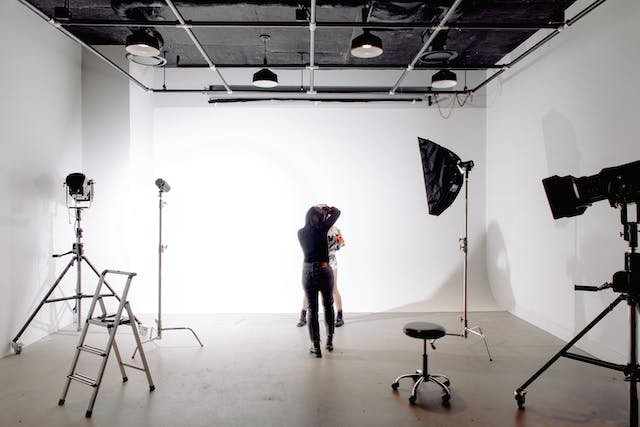 A professional photographer takes photos of a model in a studio. 