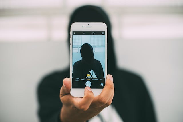 Une image montre une personne prenant un selfie à l'aide de son téléphone. 