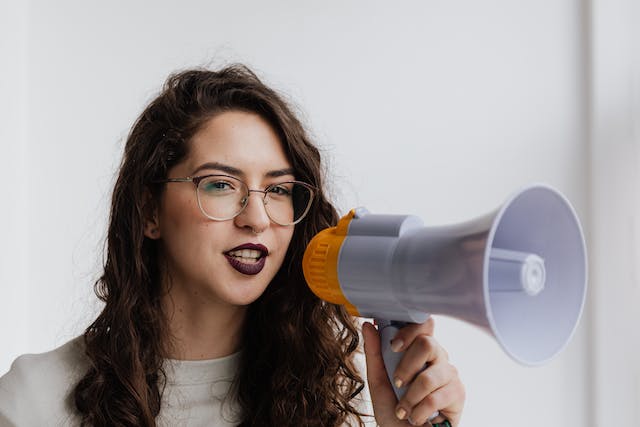 Uma mulher fala em um megafone. 