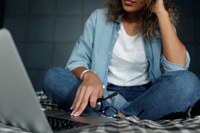 Uma mulher está sentada em frente ao seu laptop. 