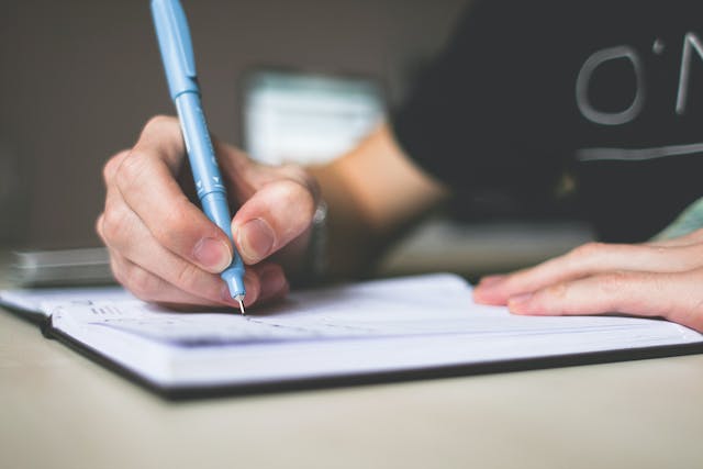 A person writes a list of names in a notebook. 