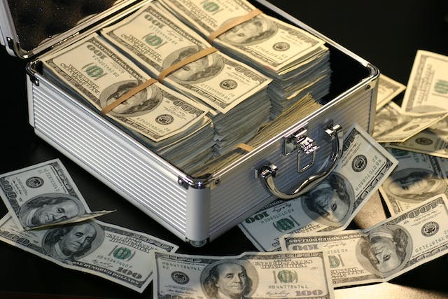 A picture of hundred dollar bills in and around a briefcase.