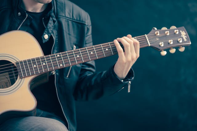 A close-up picture of a man playing a guitar. 