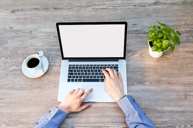 A person types a web page on a laptop. 