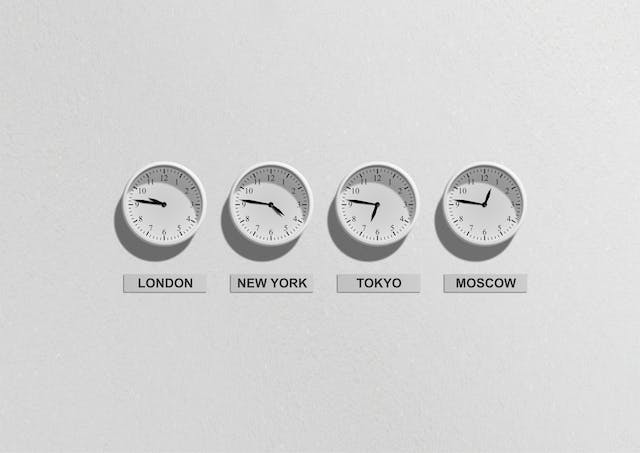 A white wall displays four clocks for different time zones. 