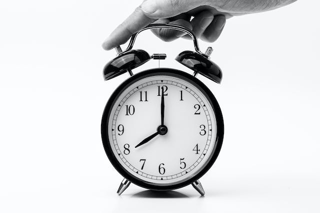 A person touches the bell of a two-bell alarm clock. 