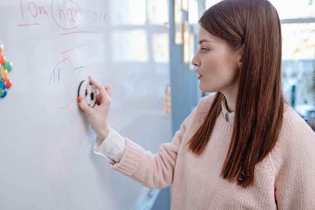 Een vrouw gumt een whiteboard uit. 