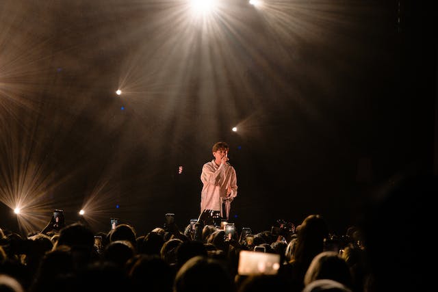 Um artista canta no palco em frente a uma grande multidão. 