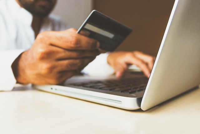 Un'immagine ravvicinata di un uomo che paga gli acquisti con la sua carta di debito in un negozio di e-commerce.