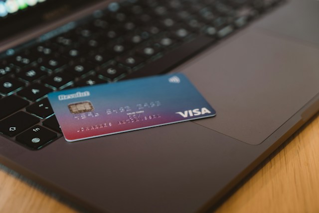 A blue Visa card on the keyboard of a laptop.