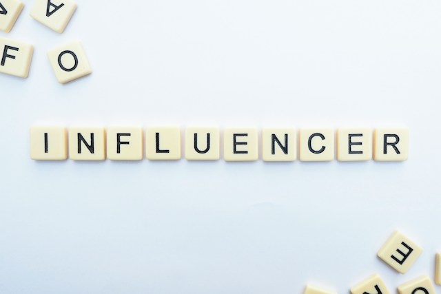 Scrabble-Kacheln auf einer weißen Fläche, die das Wort "INFLUENCER" ergeben.