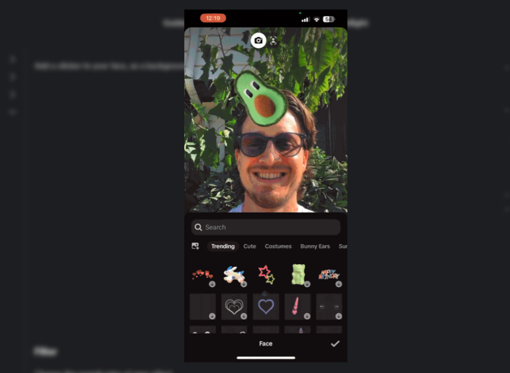 O captură de ecran a editorului de efecte pentru telefoane mobile de la TikTok prezintă un bărbat cu un autocolant de avocado pe cap și mai multe opțiuni de autocolante. 
