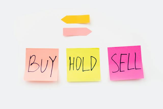 A photo of three post-its with the words “buy, hold, sell.”
