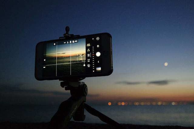 Uma imagem de um telefone com câmera em um tripé configurado para tirar uma foto do céu noturno. 