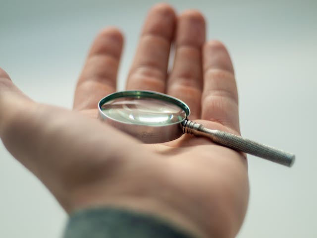 Ein kleines Vergrößerungsglas in der Hand einer Person. 