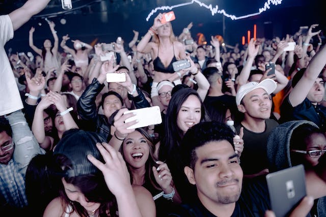 People in the audience take photos and videos with their smartphones.