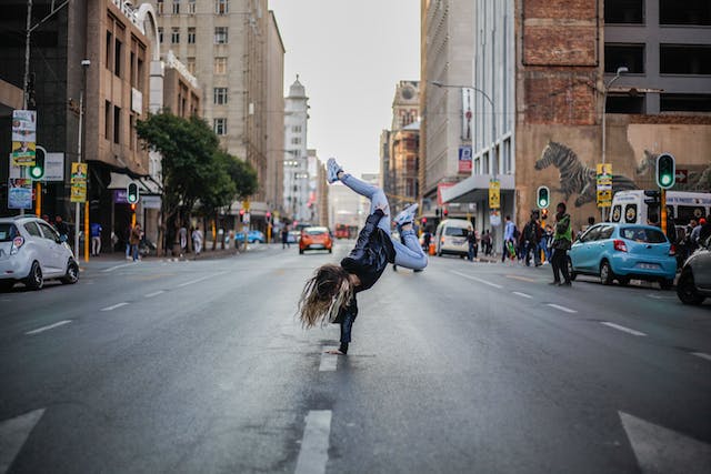 Een foto van een vrouw die midden op straat aan het breakdancen is. 