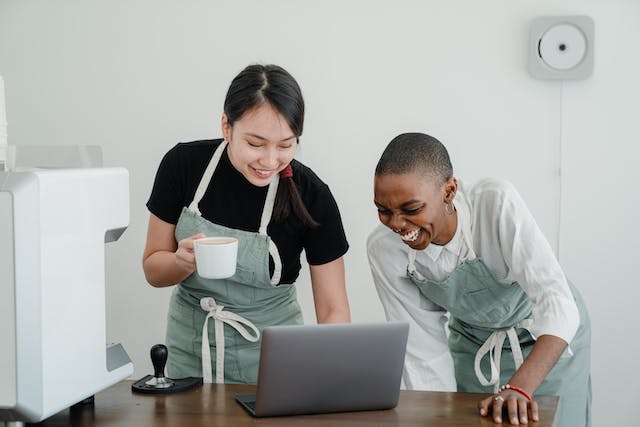 Deux femmes baristas regardent des vidéos sur un ordinateur portable pendant la pause. 