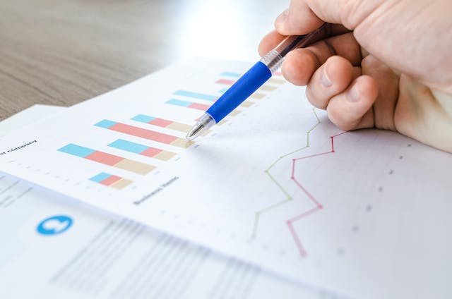 A person studies bar and line graphs printed on paper. 