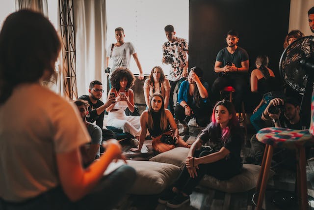 Un gruppo di persone è riunito intorno a un altoparlante in uno studio. 