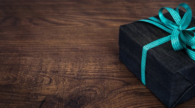 Ein Bild einer schwarzen Geschenkbox, die mit einem blauen Band umwickelt ist. 
