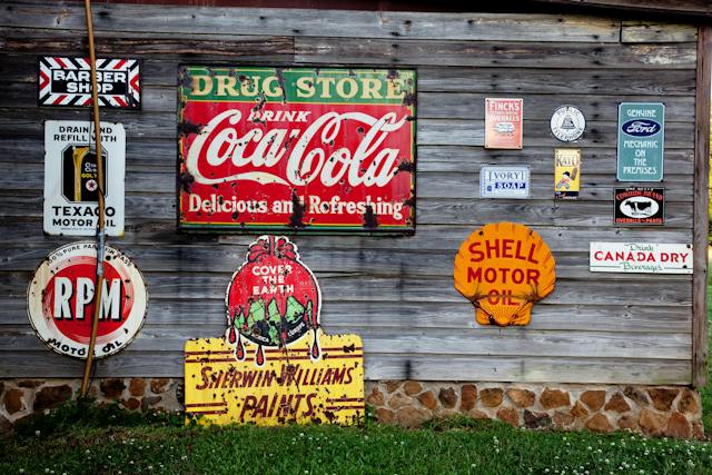 A picture of a wooden wall covered with signages of different brands. 