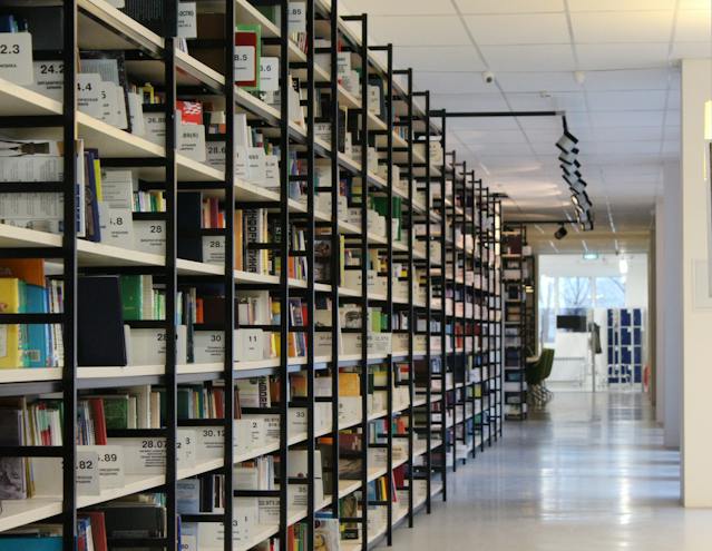 Een lange bibliotheekgang vol met planken vol boeken. 