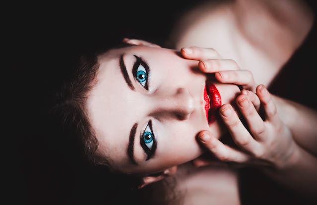 A close-up overhead shot of a woman’s face with bold makeup. 
