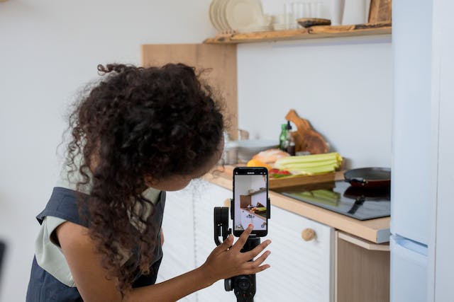 A woman presses the record button on her phone to start recording her TikTok cooking video. 