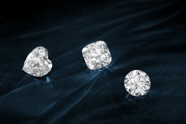 Uma imagem de três diamantes cortados em cima de um tecido. 