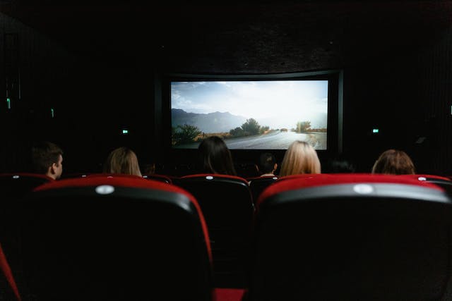 A group of people watching a movie in a dark movie theatre. 

