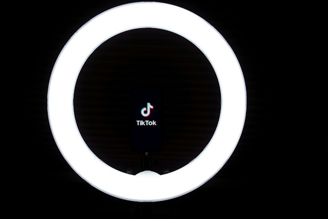 Il logo di TikTok si trova all'interno di una luce anulare bianca su sfondo nero.