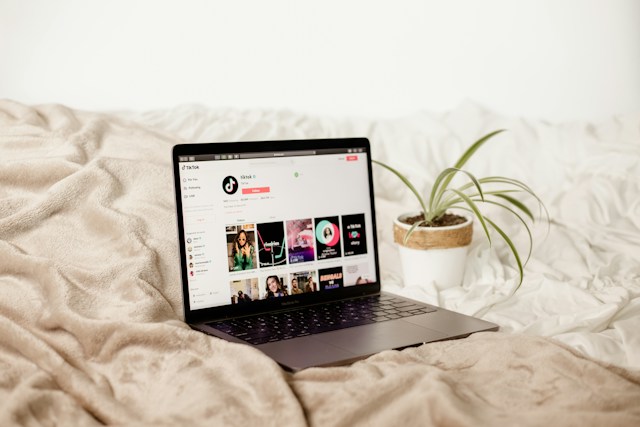 A computer on a bed shows a user’s TikTok profile.
